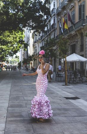 Erratic woman in flamenco dress talking on phone at street