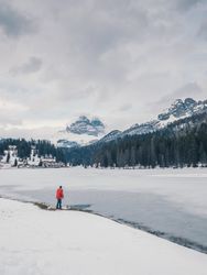 Unrecognizable person standing in snow surrounded by forest and mountains