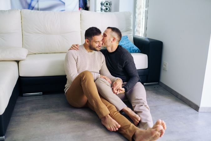 Cute male couple kissing relaxing on floor at home