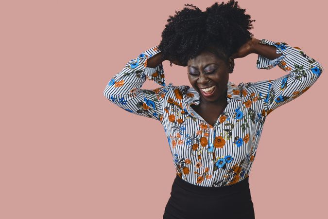 Portrait of joyful Black woman running her hands through her hair