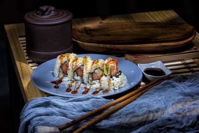 Tasty sushi poured with sauce on blue plate