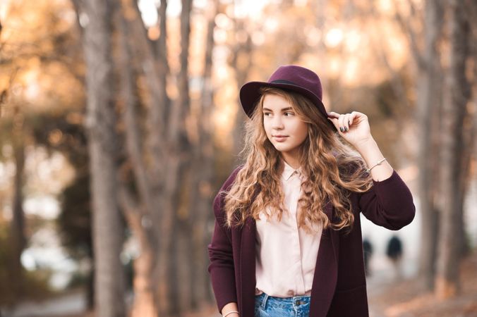Portrait of teenage girl with purple hat standing in the woods