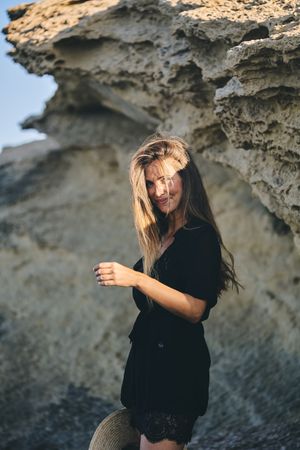 Cheerful woman holding hat in air