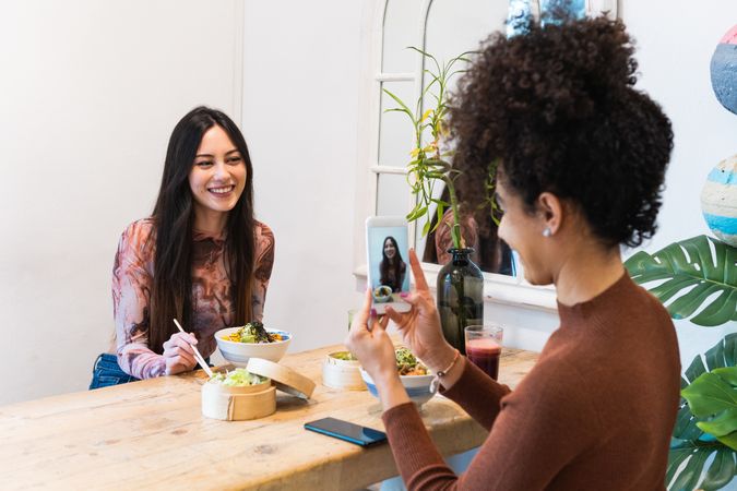 Woman taking photo of friend in restaurant