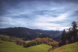 Green field in front of rolling hills on overcast day
