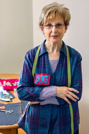 Mature dressmaker posing with sewing materials