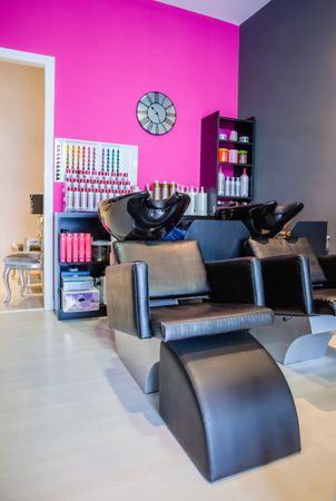 Chair for hair washing against pink wall in salon