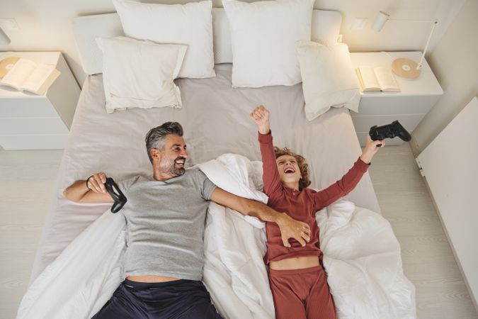 Joyful father and son having fun on bed