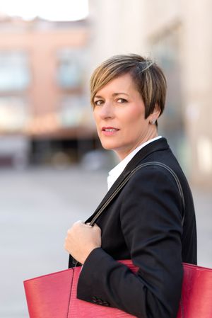 Serious woman turning around outside holding large red hand bag