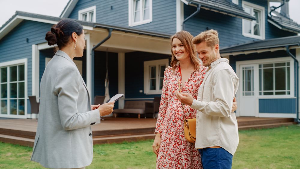 Cheerful Couple Shaking Hands with the Businesswoman and Receiving Keys From Their Property.
