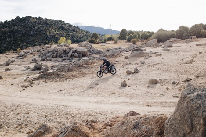 Motorcyclist on off-road track with shrubs and boulders