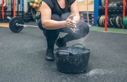 Unrecognizable woman applying magnesium to practice weightlifting