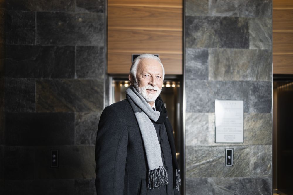 Grey breaded man wearing scarf and looking at camera