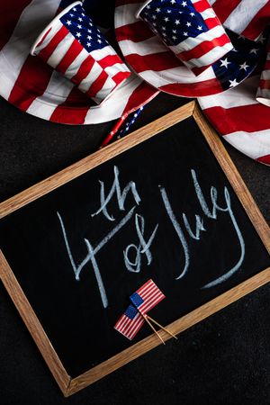 Chalkboard surrounded by USA flag plates and cups with the words "Happy 4th of July"