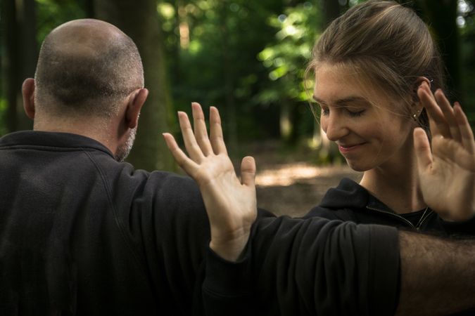 Cheerful woman practicing martial arts with trainer