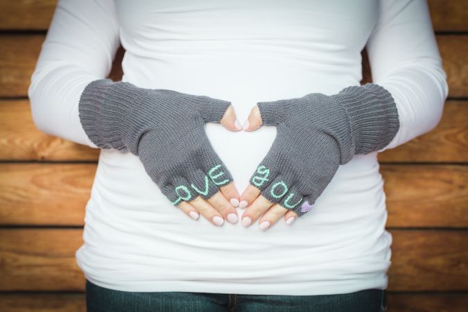 Pregnant Woman Holds Her Stomach with Love You Mittens