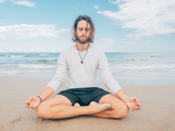 Man training yoga on beach