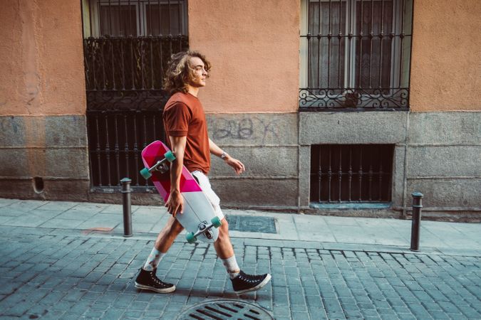 Man carrying longboard on the street