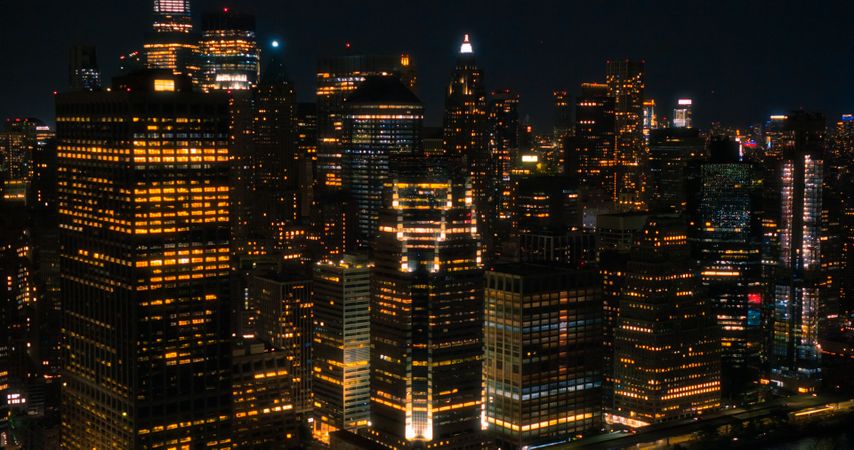 Wall Street Office Buildings Lit Up at Night: Scenic Aerial New York City View of Lower Manhattan Architecture. Panoramic Financial District Photo from a Helicopter. Evening Cityscape of NYC