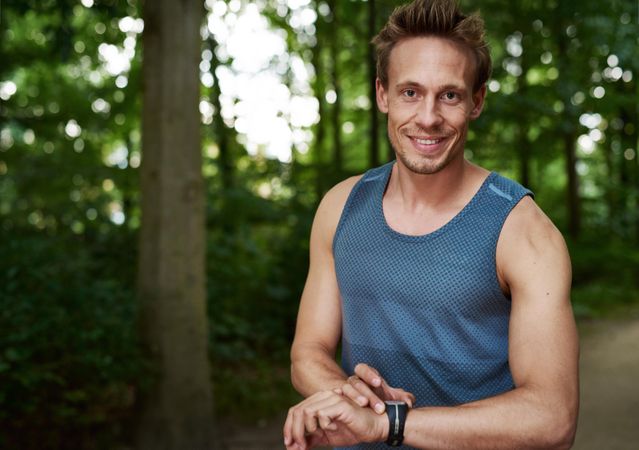 Man smiling at camera in the park before exercising