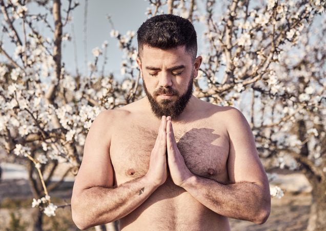 Shirtless man meditating in spring garden