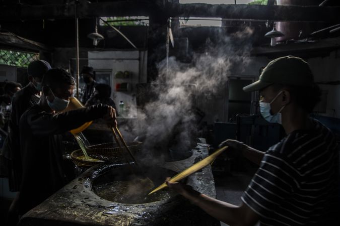 Group of workers with facemasks cooking for producing glossy noodles in Bogor, Indonesia