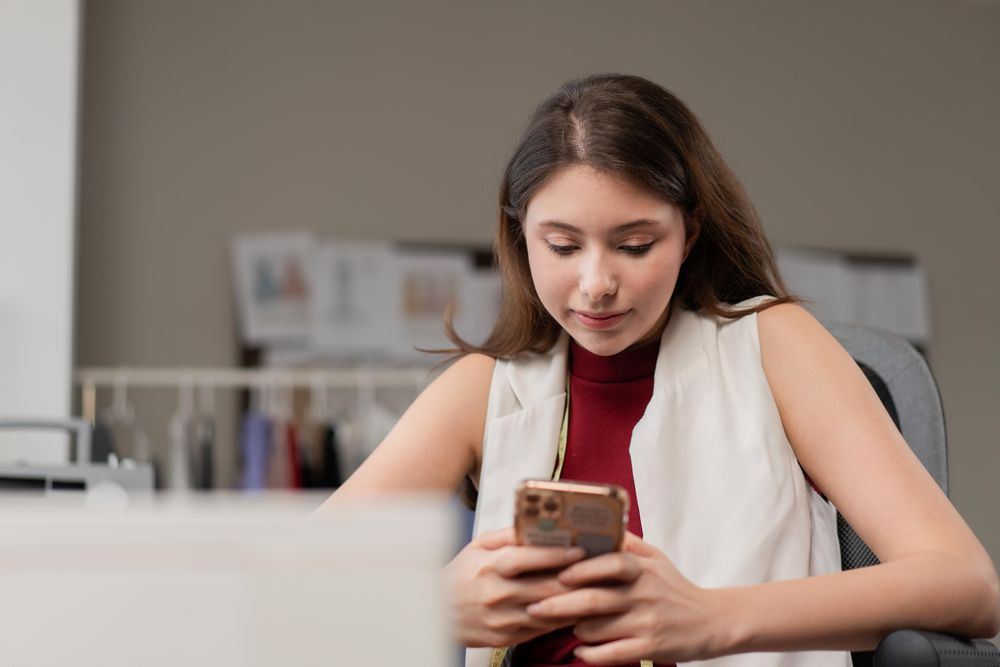 Young fashion designer check smartphone call to customer at office studio