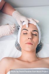 Aesthetician's hands injecting botox into female's forehead in a beauty salon 5oDMWz