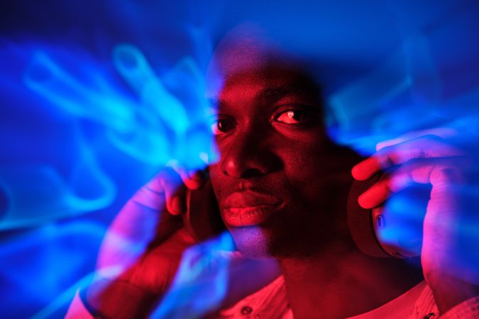 Serious Black man in headphones in colorful illumination
