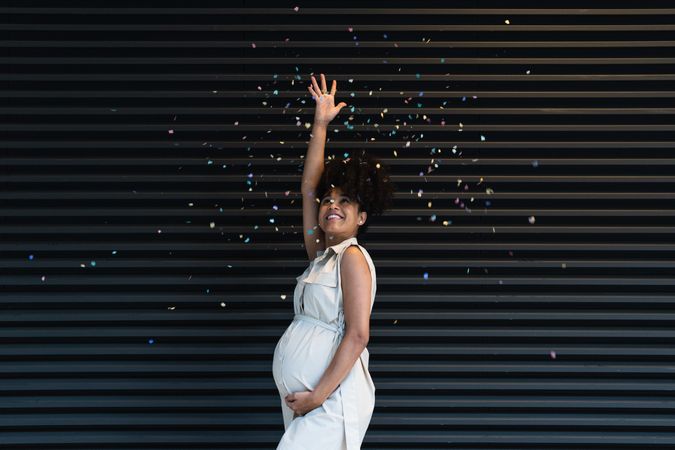 Happy Black pregnant woman throwing confetti