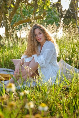 Woman sitting on plaid in verdant lush park