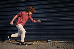 Little skater running near skateboard