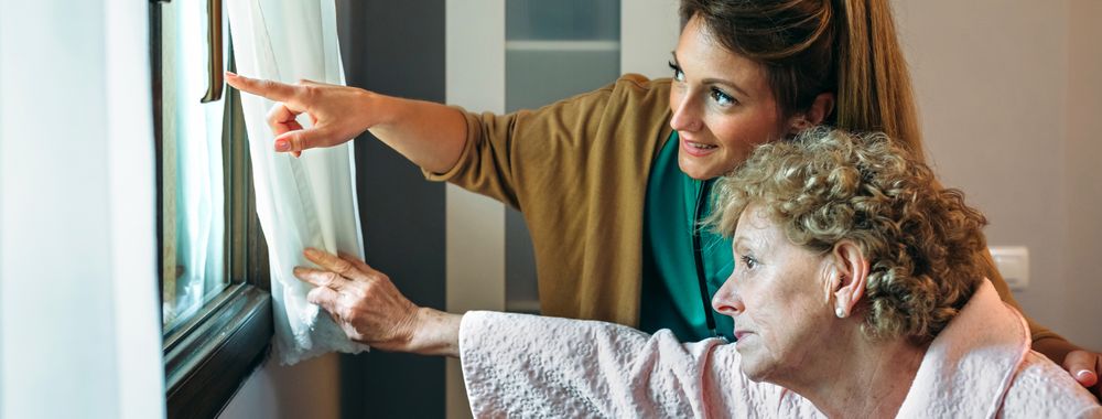 Caregiver showing the view through the window to mature patient