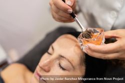 Unrecognizable beautician with client preparing product with brush 49mlon