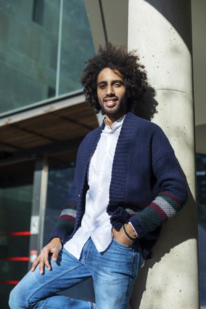 Portrait of Black man in cardigan and jeans standing outside on sunny day