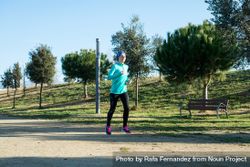Woman in ear warmers running outdoors on sunny fall day 5qd6Y0