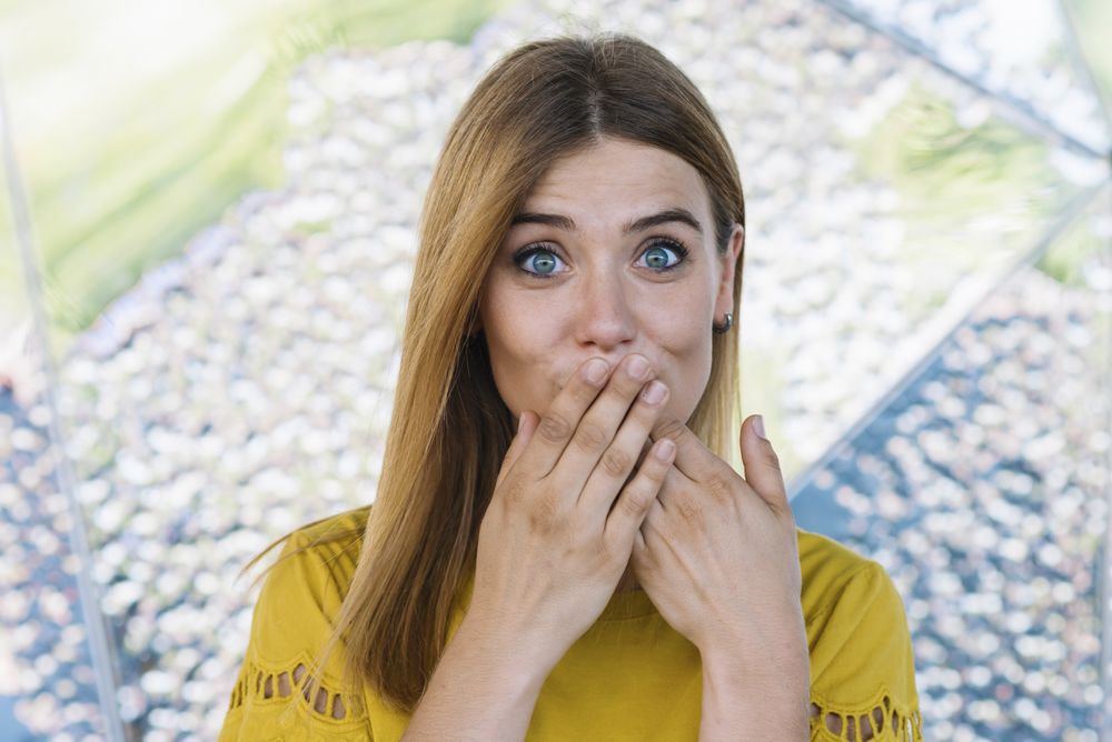 Young shy woman covering mouth