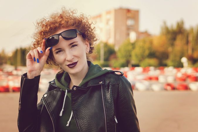 Young woman with curly hairstyle with violet lips in urban