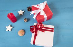 Gifts and lit candle on blue table