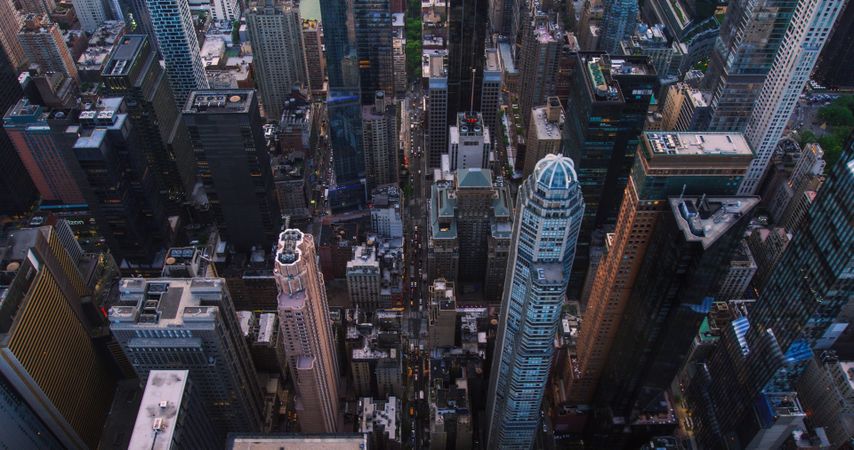 Dark Aerial Evening Shot of New York City with Straight Busy Streets with Cars and Yellow Taxi Vehicles. Lowered Helicopter View of Office Buildings and Skyscrapers in a Big Urban Center