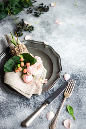 Delicate pink flowers on grey napkin and plate with cutlery and space for text