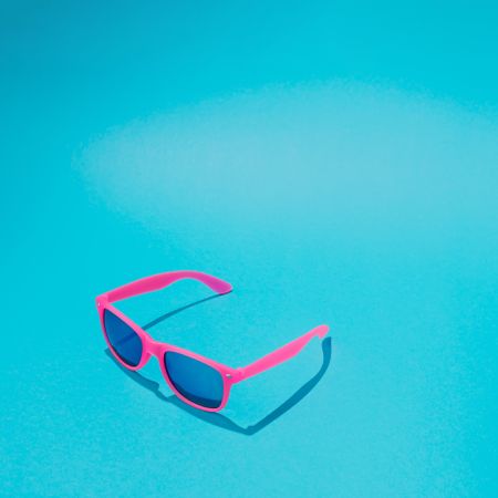 Pink sunglasses on blue background