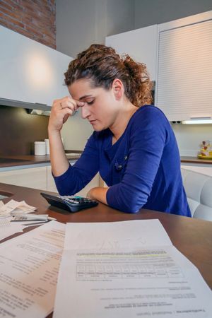 Frustrated woman with bills on her kitchen counter