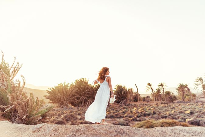 Woman in white dress in dry field in sunlight