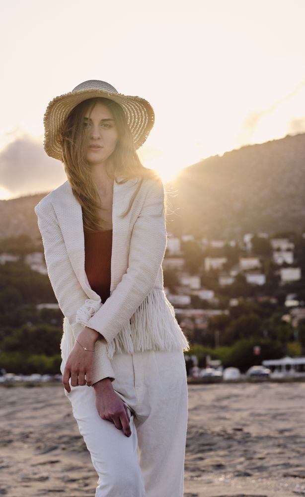 A long hair fashion model with a hat at the beach at sunset in a summer day