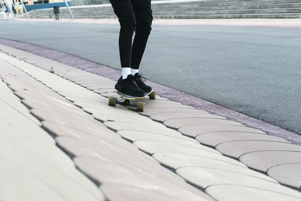 Unrecognizable woman rides on longboard around sunlit park