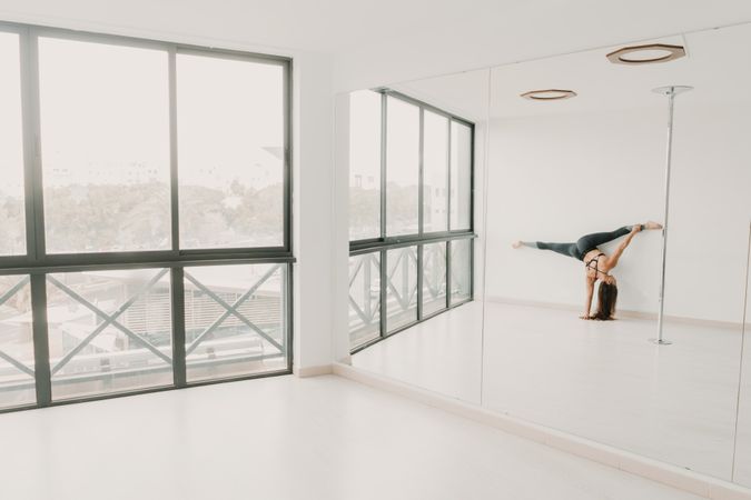 Flexible female doing handstand with legs to sides in studio