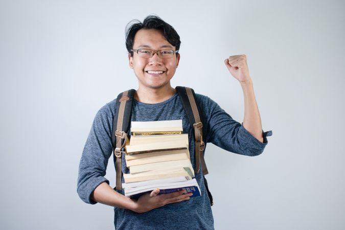 Asian student holding books and making strong gesture