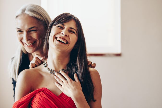 Woman laughing in happiness touching the necklace
