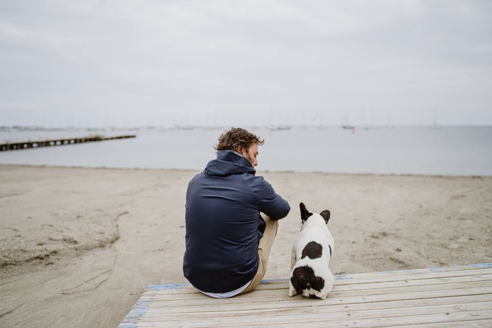 Man and dog resting on beach together